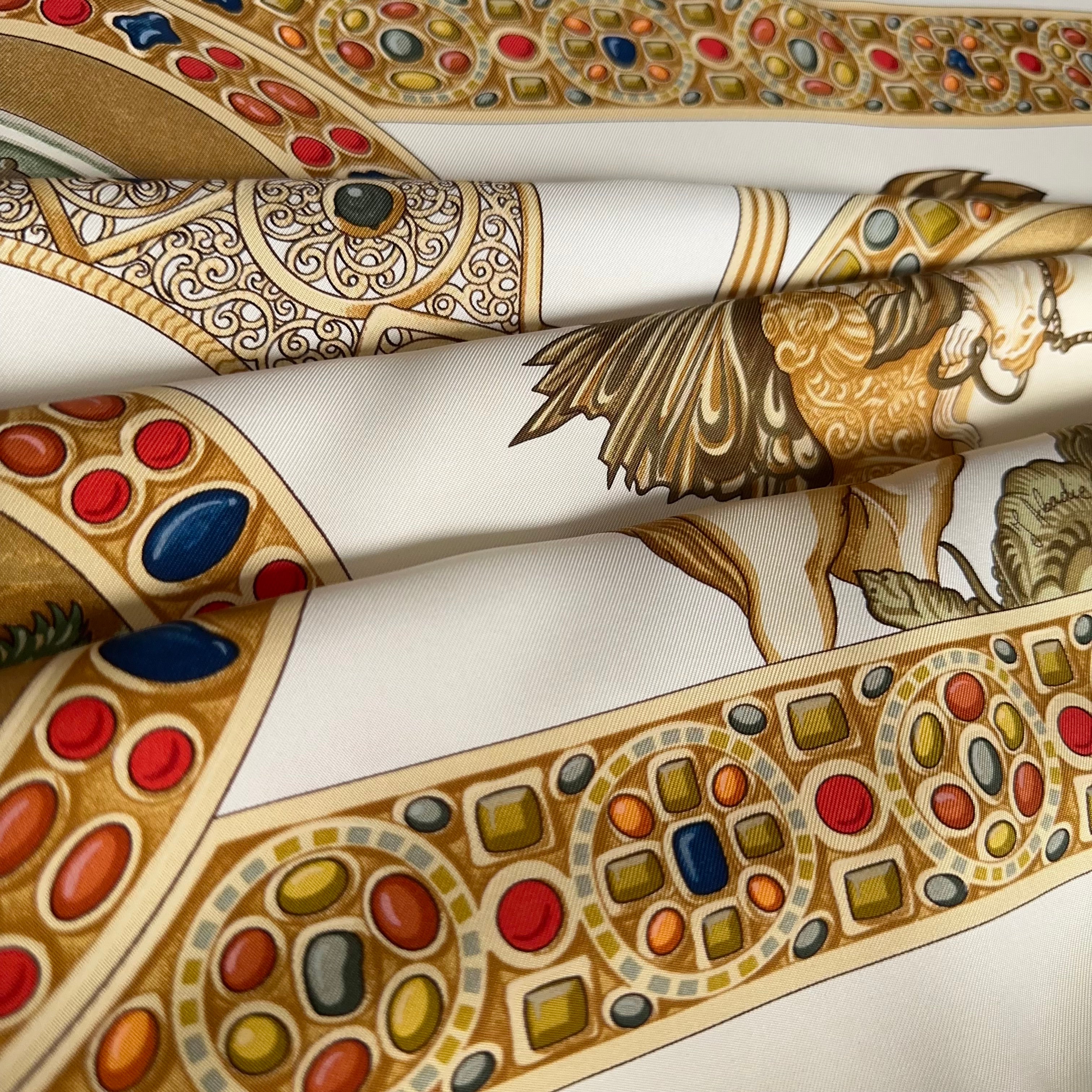 Vue artistique des plis du foulard, révélant la densité des motifs d'orfèvrerie et la brillance du twill de soie crème et or.