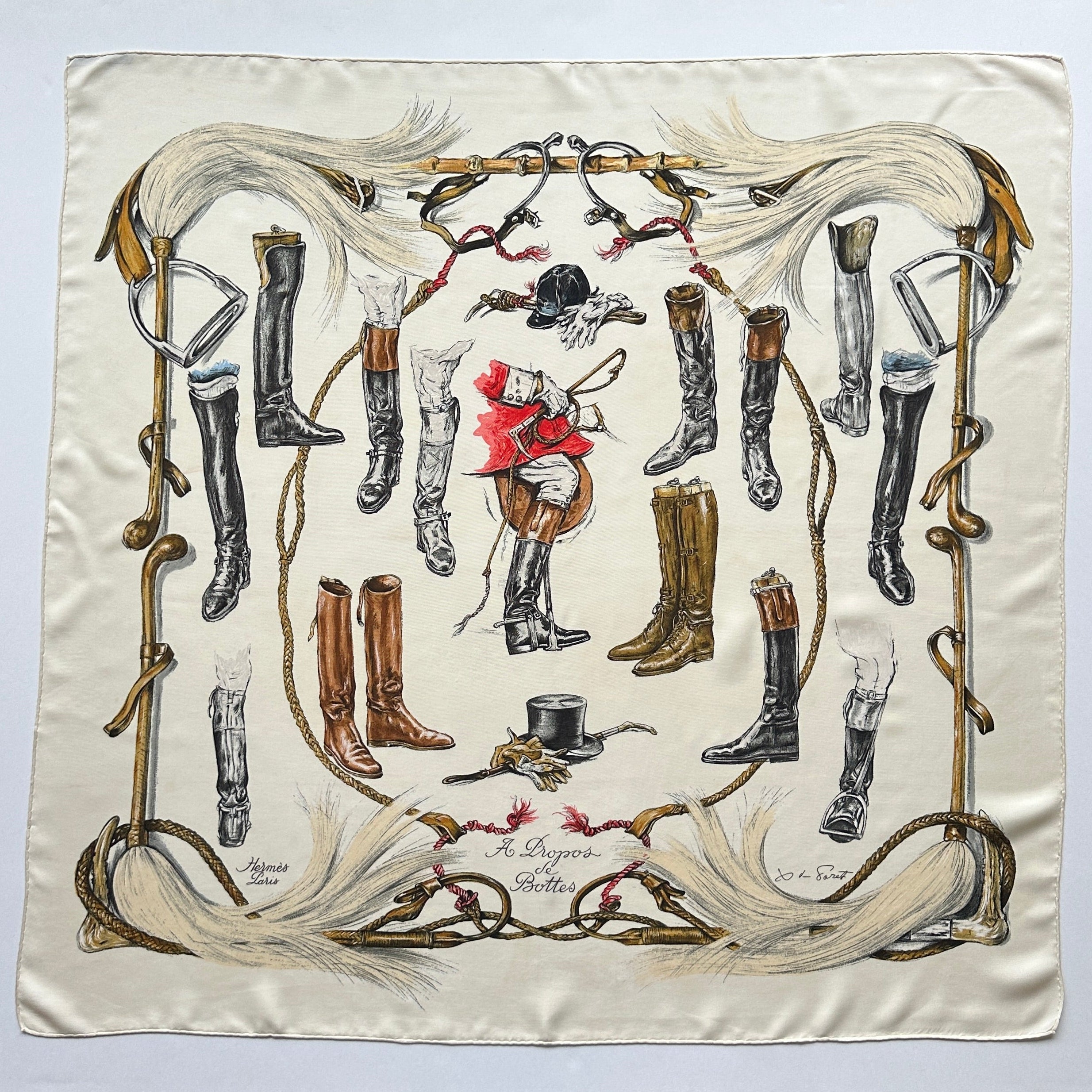 Carré Hermès "À Propos de Bottes" sur fond crème, illustrant une collection de bottes d'équitation et accessoires de chasse à courre.