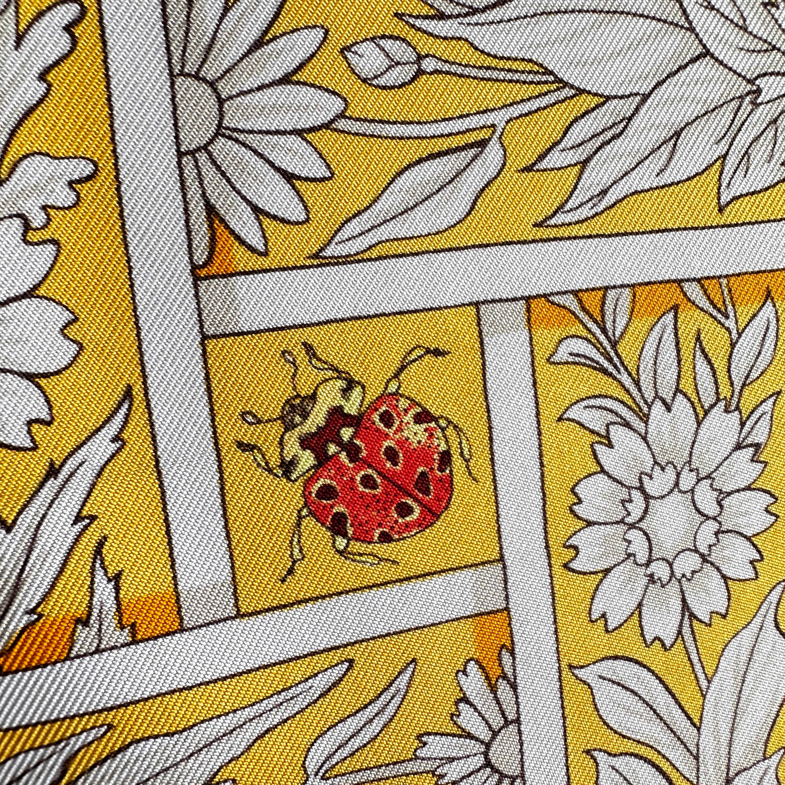 Gros plan sur un papillon coloré et une coccinelle dessinés sur la soie.